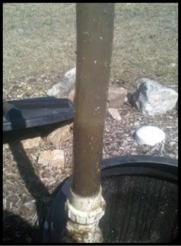 A plastic measuring pole being lowered into a septic tank.